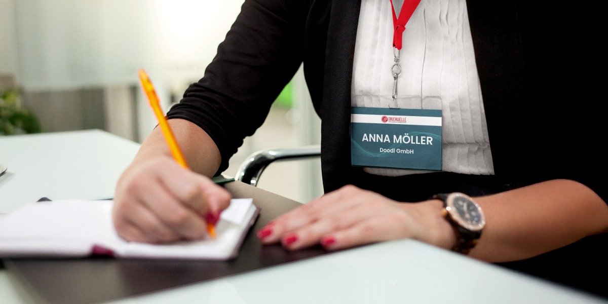 Namensschilder drucken – individuelle Event Badges von Druckwelle Bonn Mitarbeiterin mit Event-Namensschild von Druckwelle Bonn, beschriftet mit individuellem Namen und rotem Band